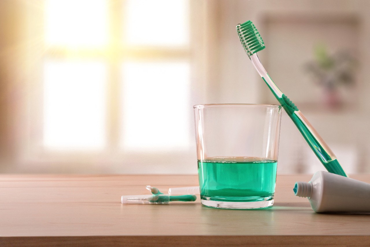 Equipment for oral hygiene on wood table in bathroom with window in the background. Horizontal composition. Front view.